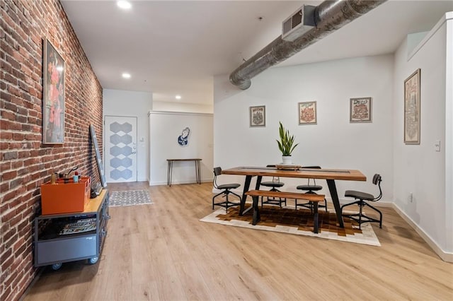 dining room featuring light hardwood / wood-style flooring and brick wall