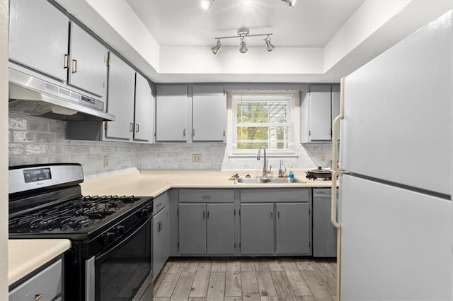 kitchen featuring light hardwood / wood-style floors, sink, appliances with stainless steel finishes, backsplash, and gray cabinetry