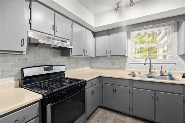 kitchen with gray cabinetry, backsplash, stainless steel range with gas cooktop, sink, and light hardwood / wood-style floors