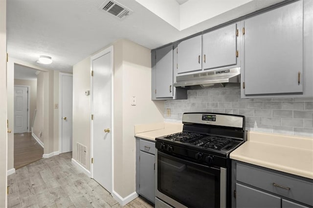 kitchen with gray cabinets, backsplash, stainless steel gas range, and light hardwood / wood-style flooring