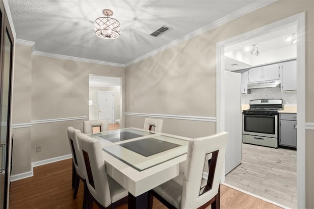 dining room featuring light hardwood / wood-style floors and crown molding