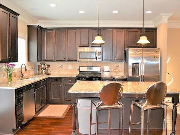 1035 Willow Field Ln SE, Marietta, GA 30067 - kitchen featuring dark wood-style floors, dark brown cabinets, ornamental molding, light stone countertops, and appliances with stainless steel finishes
