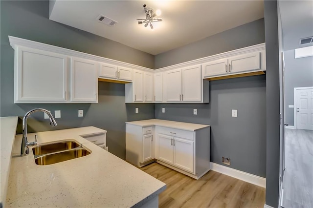 kitchen with white cabinets, light wood-type flooring, and sink