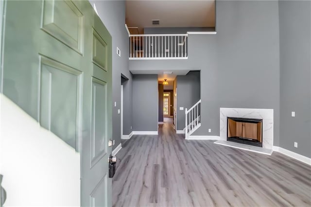 entryway with a high end fireplace, a high ceiling, and light hardwood / wood-style floors