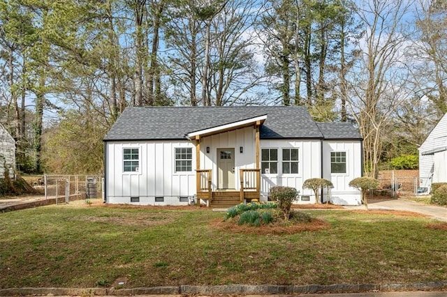 view of front of home featuring fence, roof with shingles, crawl space, a front lawn, and board and batten siding