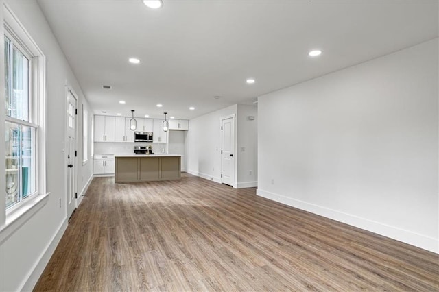 unfurnished living room with recessed lighting, visible vents, baseboards, and wood finished floors