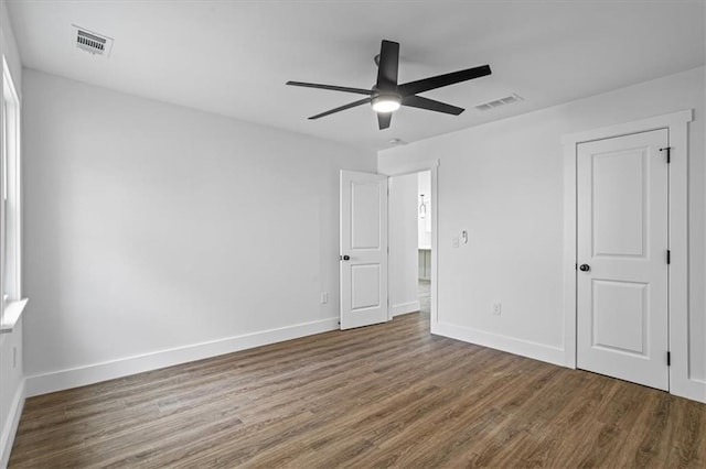 unfurnished bedroom featuring dark wood-type flooring, visible vents, and baseboards