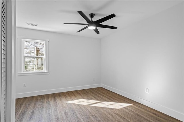 spare room featuring visible vents, ceiling fan, baseboards, and wood finished floors