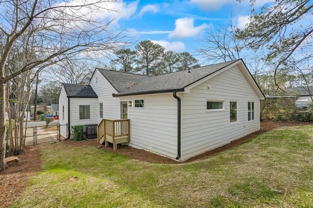 rear view of house with a gate, fence, a lawn, and roof with shingles