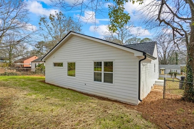 view of side of property with a yard, roof with shingles, and fence