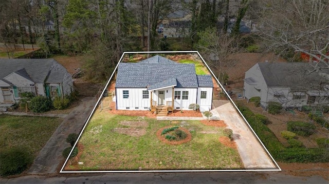 view of front of house with driveway, a front lawn, board and batten siding, and a shingled roof