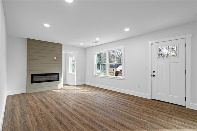 unfurnished living room with a large fireplace, baseboards, dark wood-style floors, and recessed lighting