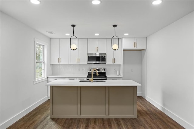 kitchen featuring a center island with sink, white cabinetry, stainless steel appliances, and light countertops