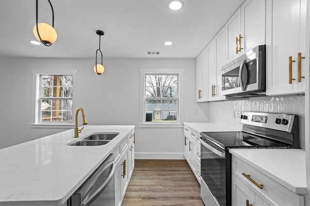 kitchen featuring hanging light fixtures, appliances with stainless steel finishes, a sink, and white cabinetry