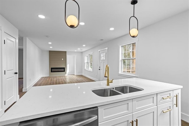 kitchen featuring hanging light fixtures, stainless steel dishwasher, open floor plan, white cabinetry, and a sink