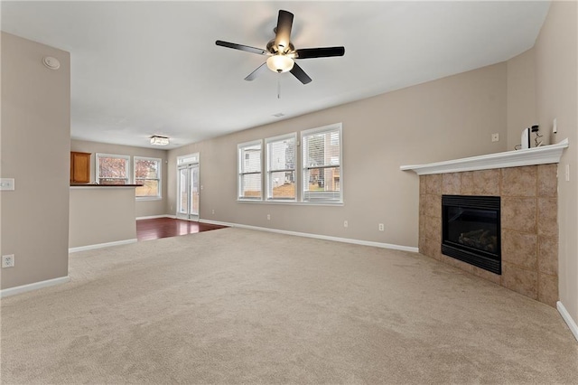 unfurnished living room featuring a tiled fireplace, light carpet, and ceiling fan