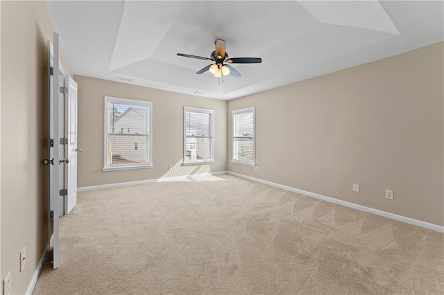 carpeted spare room featuring a tray ceiling and ceiling fan