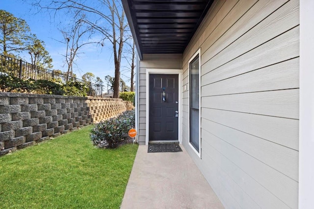 view of exterior entry with a yard and fence