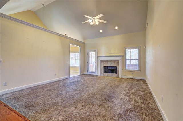 unfurnished living room with carpet flooring, ceiling fan, high vaulted ceiling, and a tile fireplace