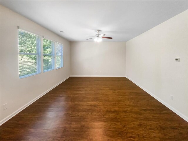 empty room with ceiling fan and dark hardwood / wood-style flooring