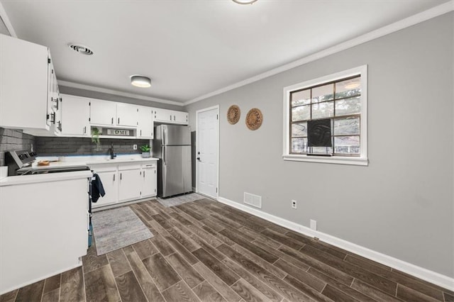 kitchen with dark hardwood / wood-style flooring, tasteful backsplash, crown molding, white cabinetry, and stainless steel refrigerator