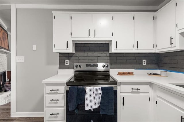 kitchen with white cabinetry, a brick fireplace, dark hardwood / wood-style floors, stainless steel electric stove, and decorative backsplash