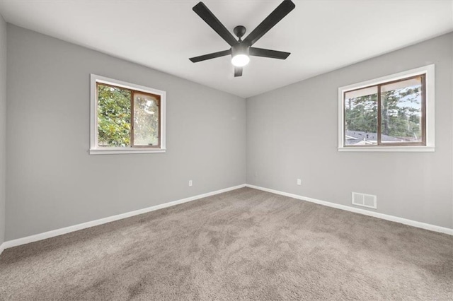 carpeted empty room featuring ceiling fan and plenty of natural light