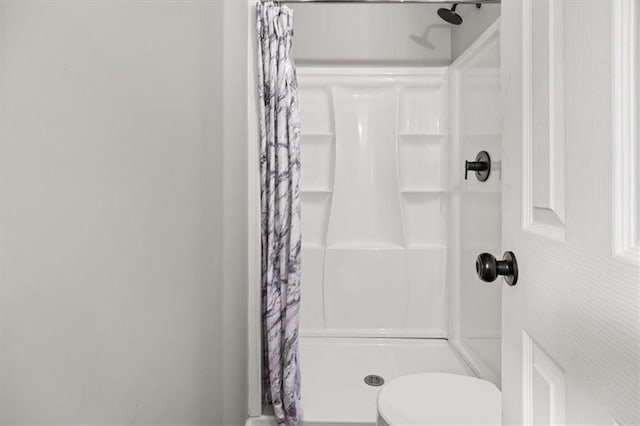 bathroom with a shower with shower curtain and toilet