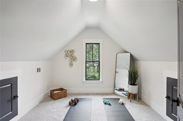 exercise room featuring light colored carpet and lofted ceiling