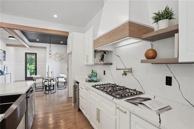 kitchen with decorative backsplash, light stone countertops, white cabinetry, and appliances with stainless steel finishes