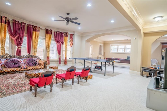 recreation room with ceiling fan, ornamental molding, and light carpet