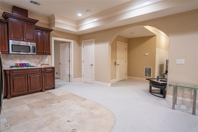 kitchen featuring backsplash, light carpet, ornamental molding, appliances with stainless steel finishes, and dark brown cabinetry