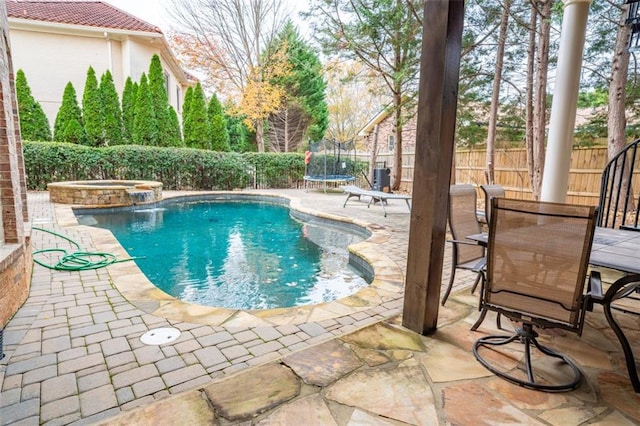 view of swimming pool featuring an in ground hot tub, a patio, and a trampoline