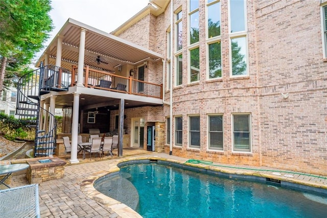 view of swimming pool featuring a fire pit, ceiling fan, and a patio area