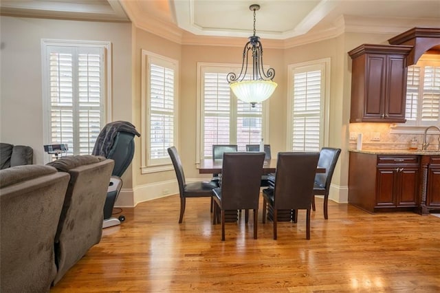 dining room featuring sink, light wood-type flooring, and crown molding