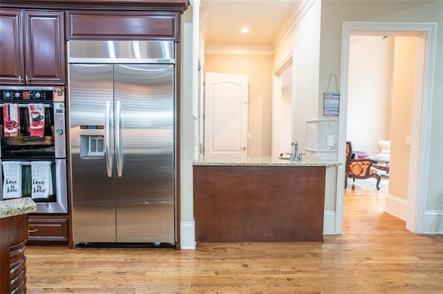 kitchen featuring light hardwood / wood-style floors, light stone countertops, and appliances with stainless steel finishes