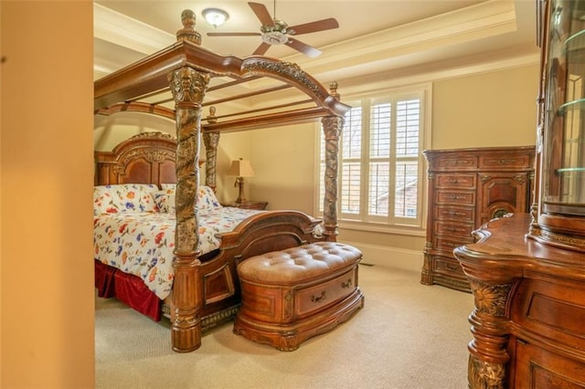 bedroom featuring light carpet, a tray ceiling, ceiling fan, and ornamental molding