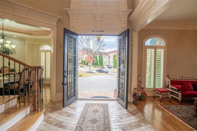 foyer entrance featuring light wood-type flooring, a notable chandelier, and ornamental molding