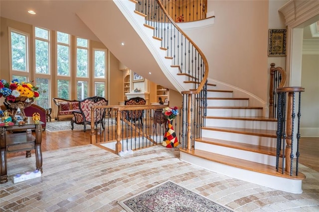 staircase with hardwood / wood-style floors and a towering ceiling