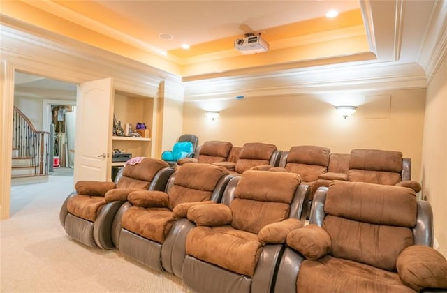 home theater featuring a raised ceiling, crown molding, and light colored carpet