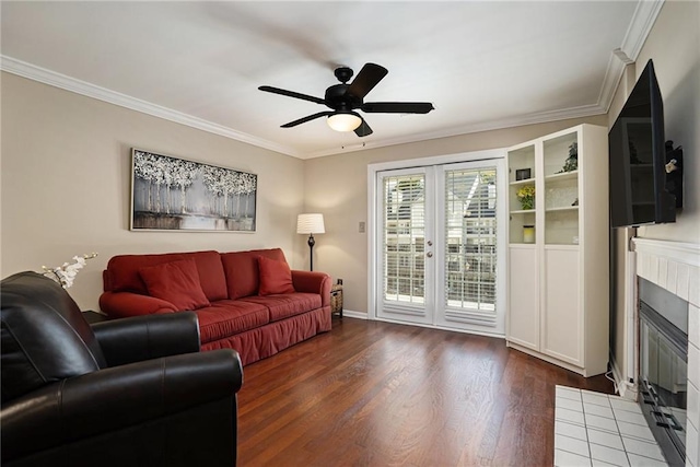 living room with ceiling fan, crown molding, a tile fireplace, and dark hardwood / wood-style flooring