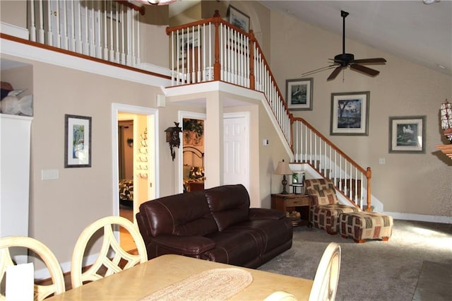 carpeted living area featuring high vaulted ceiling, ceiling fan, stairway, and baseboards