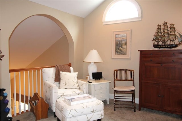 sitting room featuring lofted ceiling, arched walkways, and light colored carpet