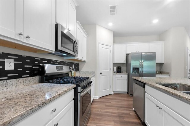 kitchen featuring white cabinets, wood finished floors, visible vents, a sink, and appliances with stainless steel finishes
