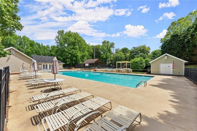 1172 Malvern Hunt Ct, Lawrenceville, GA 30043 - community pool featuring fence, a patio, view of wooded area, and an outbuilding
