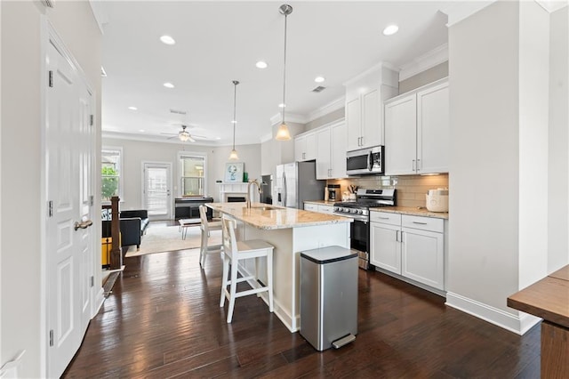 4458 Dunblane Ave, Sugar Hill, GA 30518 - kitchen with stainless steel appliances, a center island with sink, white cabinets, decorative backsplash, and crown molding