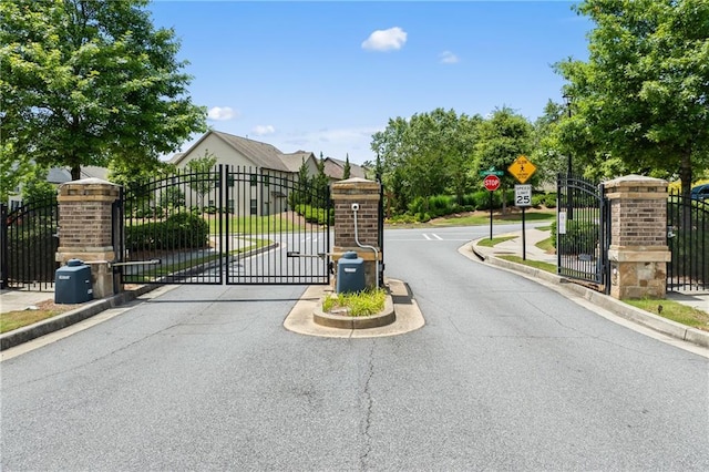 4458 Dunblane Ave, Sugar Hill, GA 30518 - view of asphalt road featuring a gate, traffic signs, a gated entry, curbs, and sidewalks