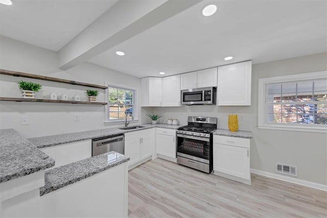 kitchen featuring light stone countertops, light hardwood / wood-style flooring, white cabinets, and appliances with stainless steel finishes