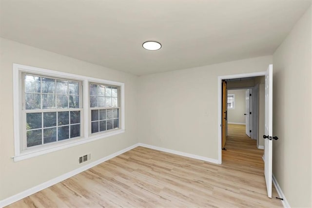 empty room with a healthy amount of sunlight and light hardwood / wood-style floors