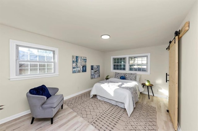 bedroom with a barn door and light hardwood / wood-style floors